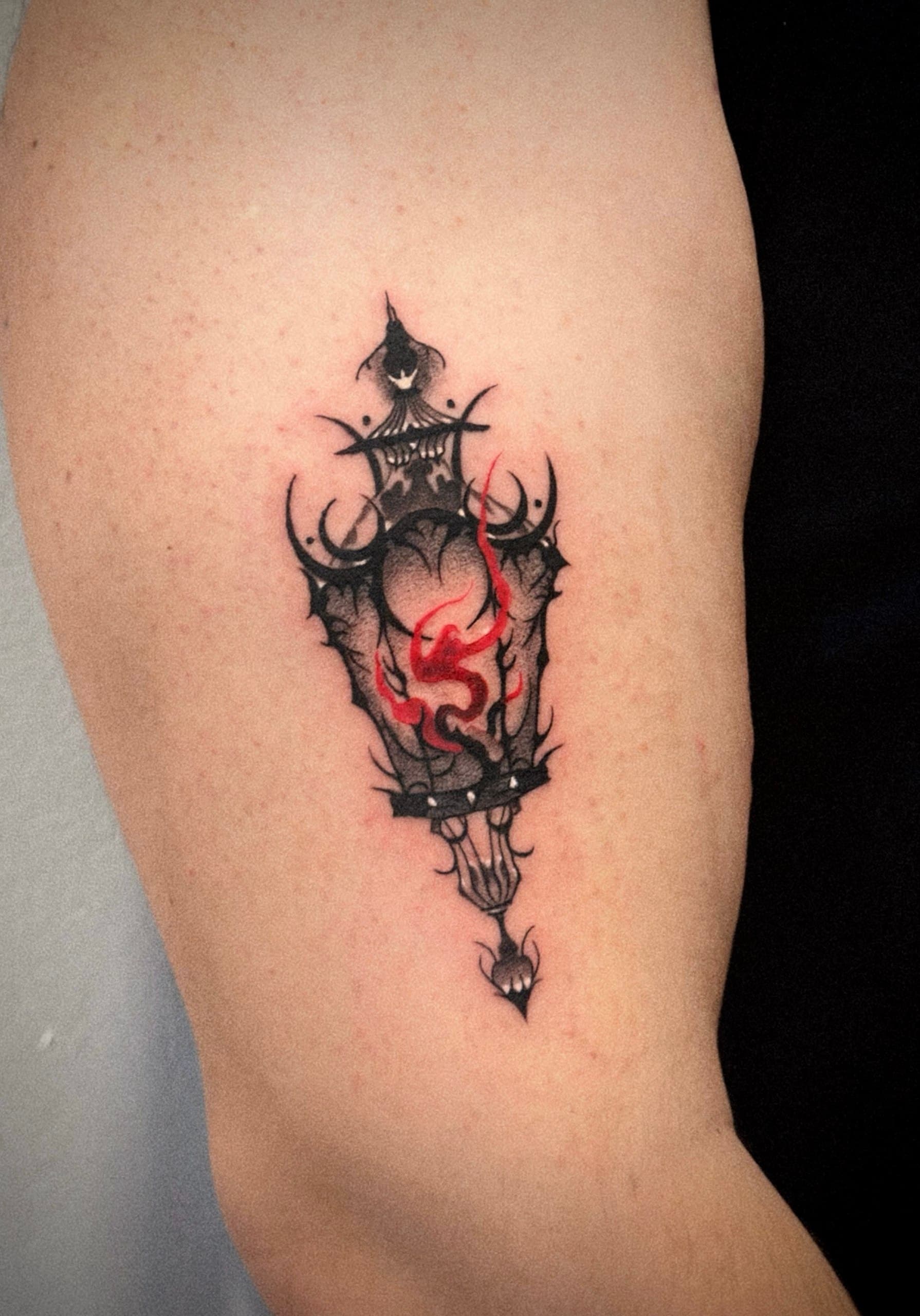 Black and red ornamental lantern tattoo on the upper arm