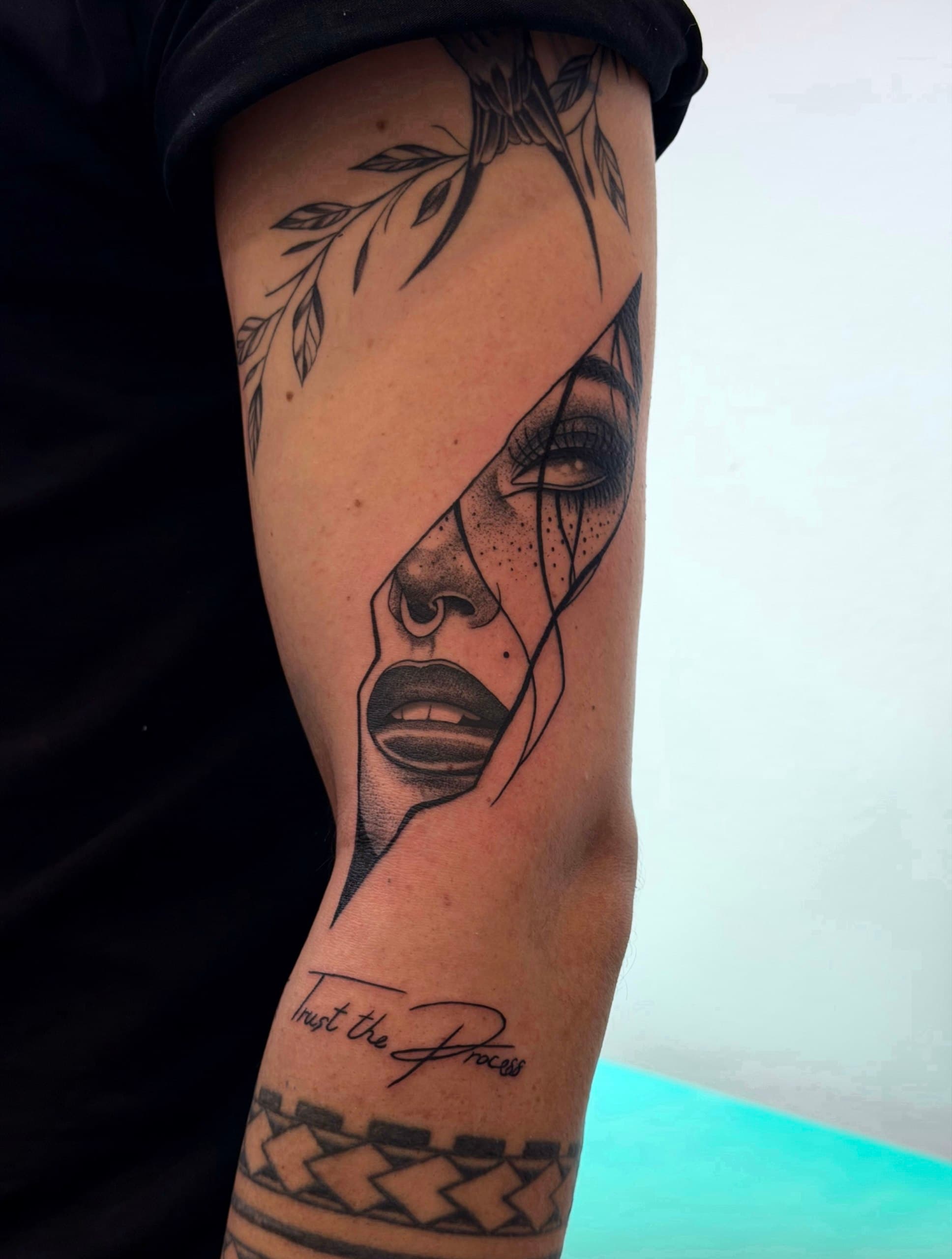 Blackwork portrait tattoo with a floral branch on the arm