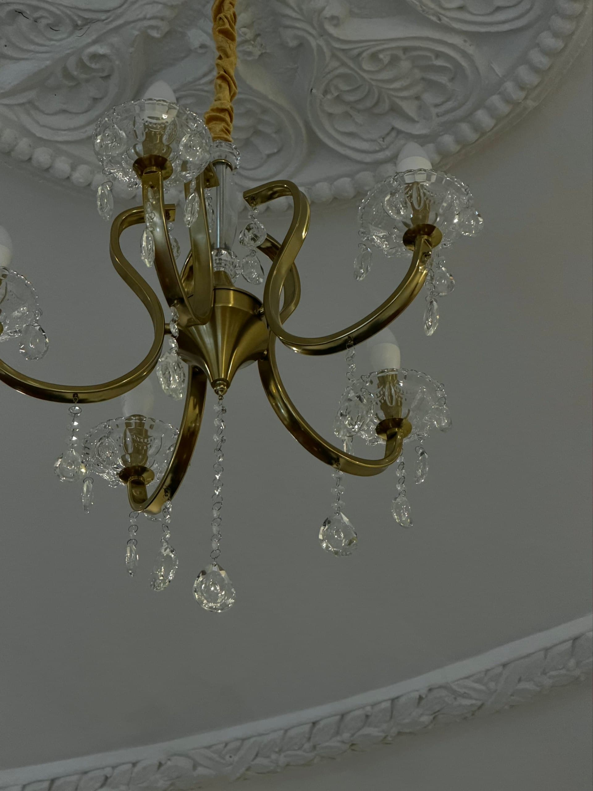 Brass and crystal chandelier under a classic stucco ceiling