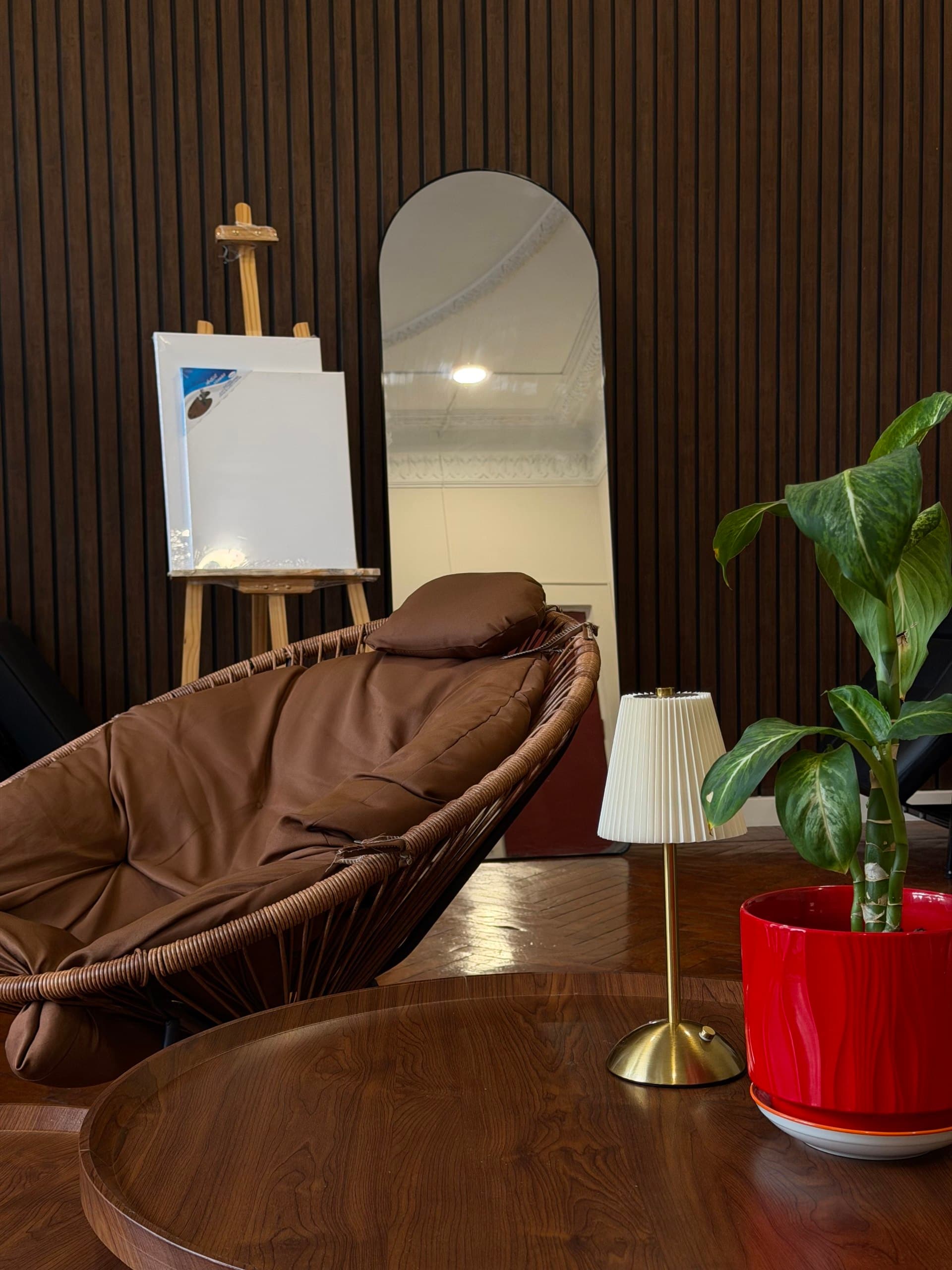 Cozy lounge corner with wicker chair, easel and arched mirror